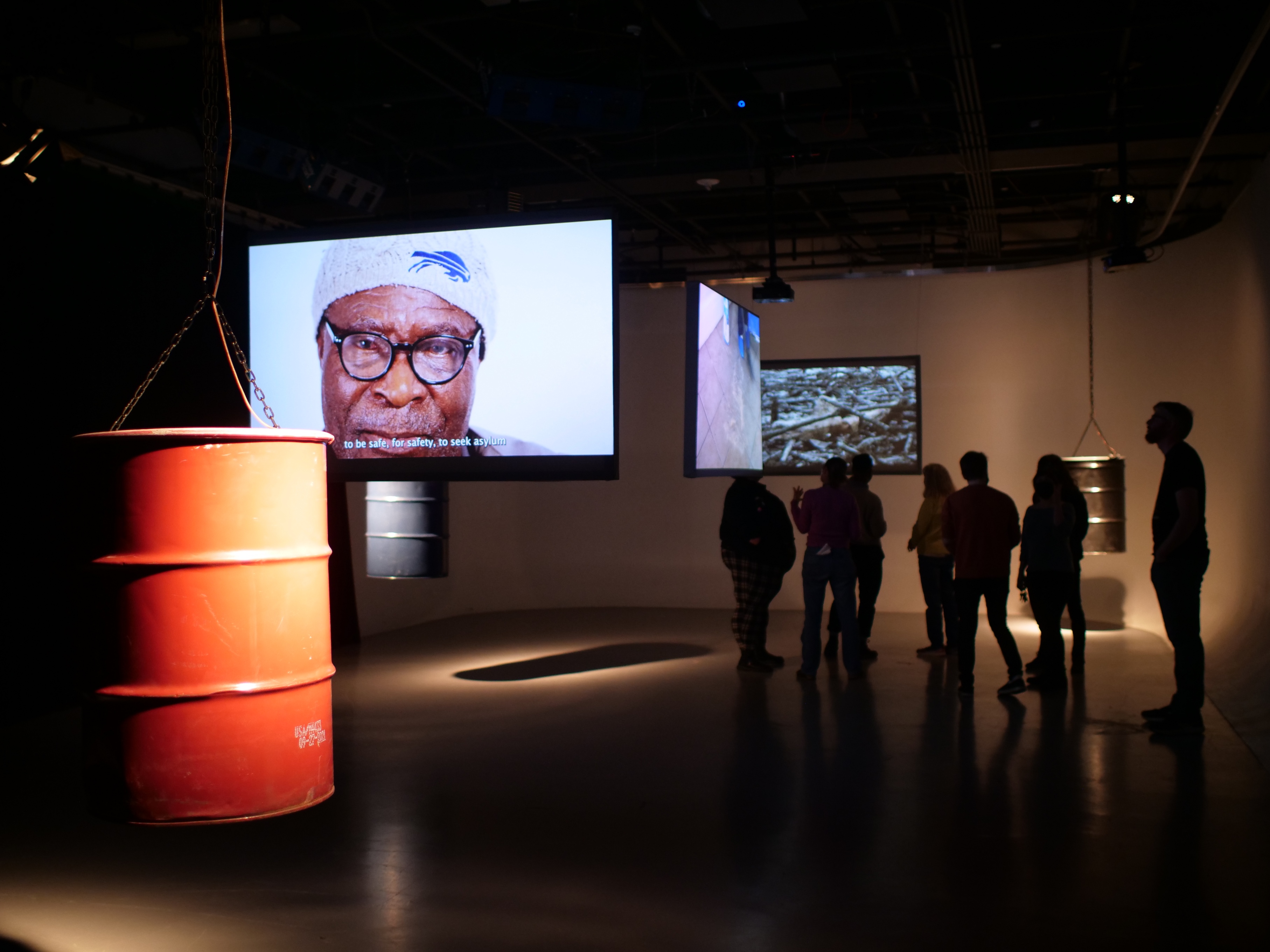 3 oil drums and 3 rear projections inside gallery, University at Buffalo (2022)