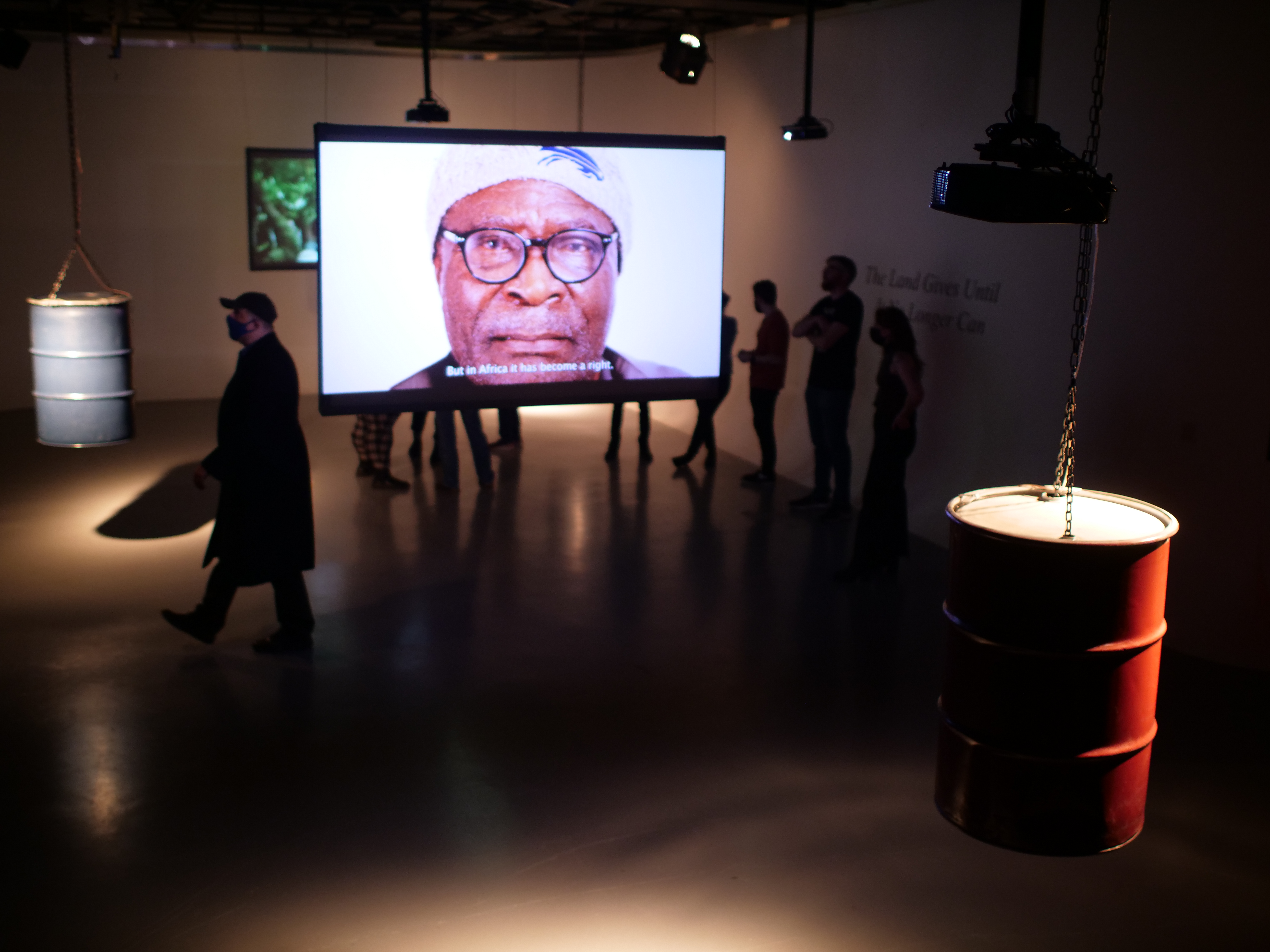 Audience engaging with suspended oil drums and screens
